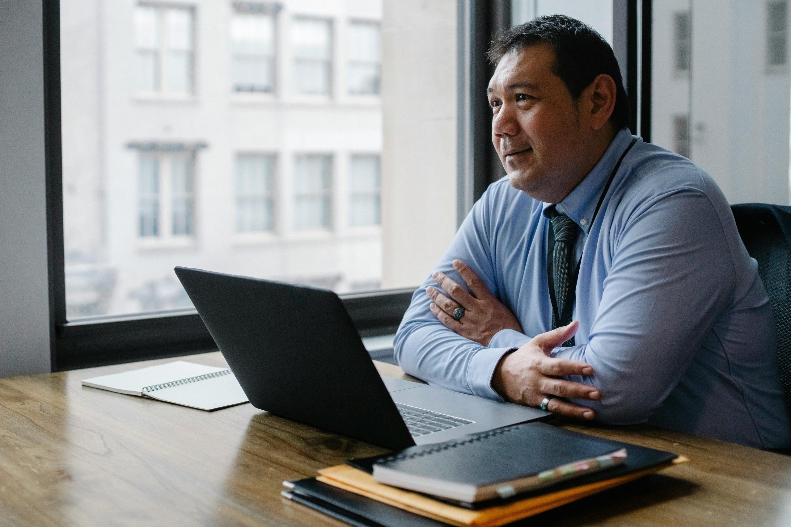 Positive ethnic boss using laptop in light office